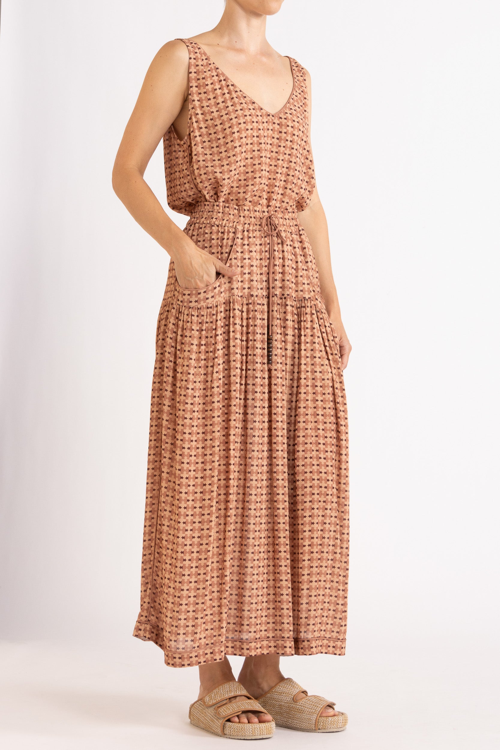 Model wearing peach patterned tank and skirt, front-side view