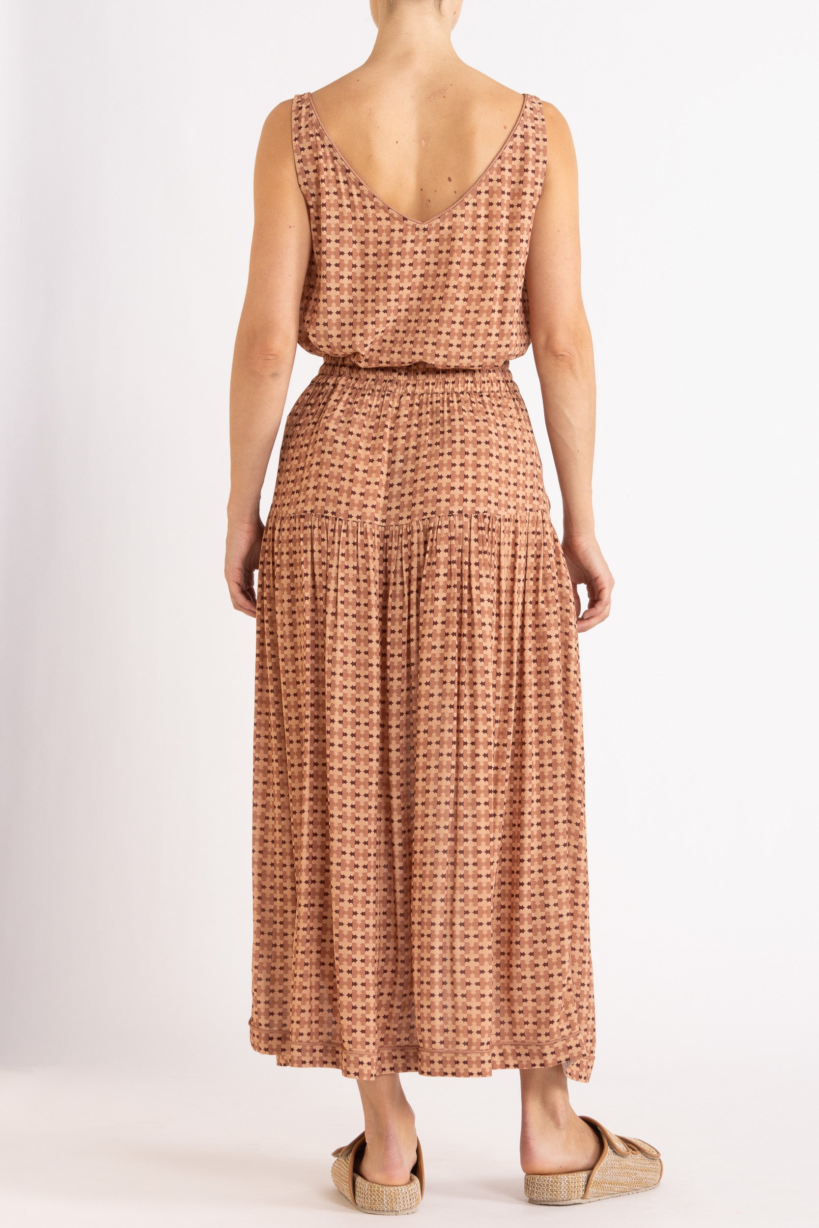 Model wearing peach patterned tank and skirt, back view