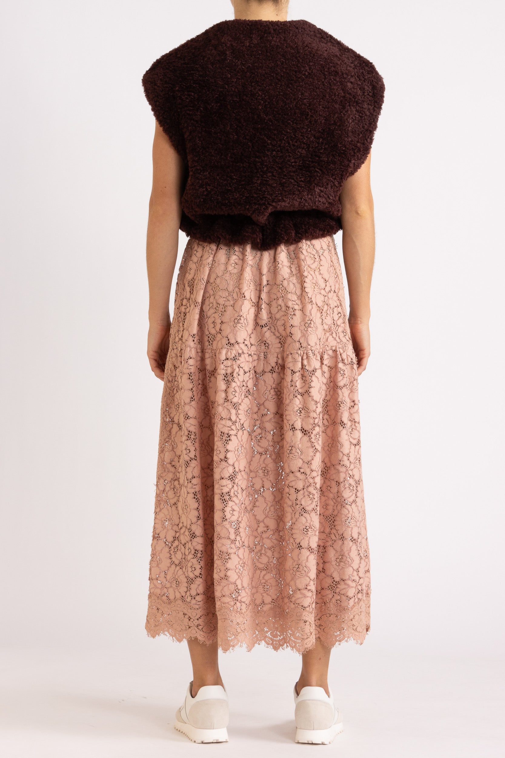 woman wearing a port coloured faux fur zip up vest with a rouge floral dress