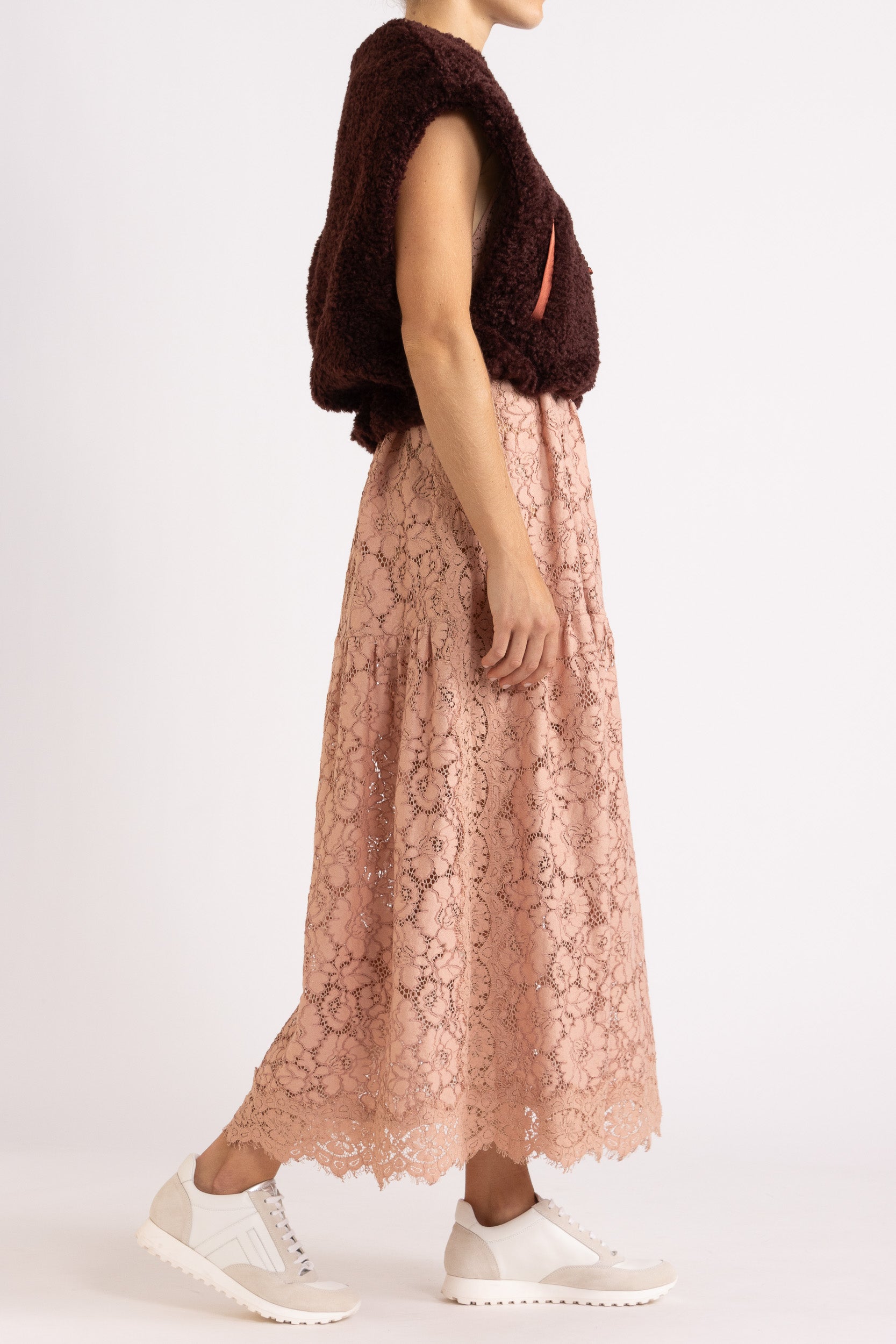 woman wearing a port coloured faux fur zip up vest with a rouge floral dress