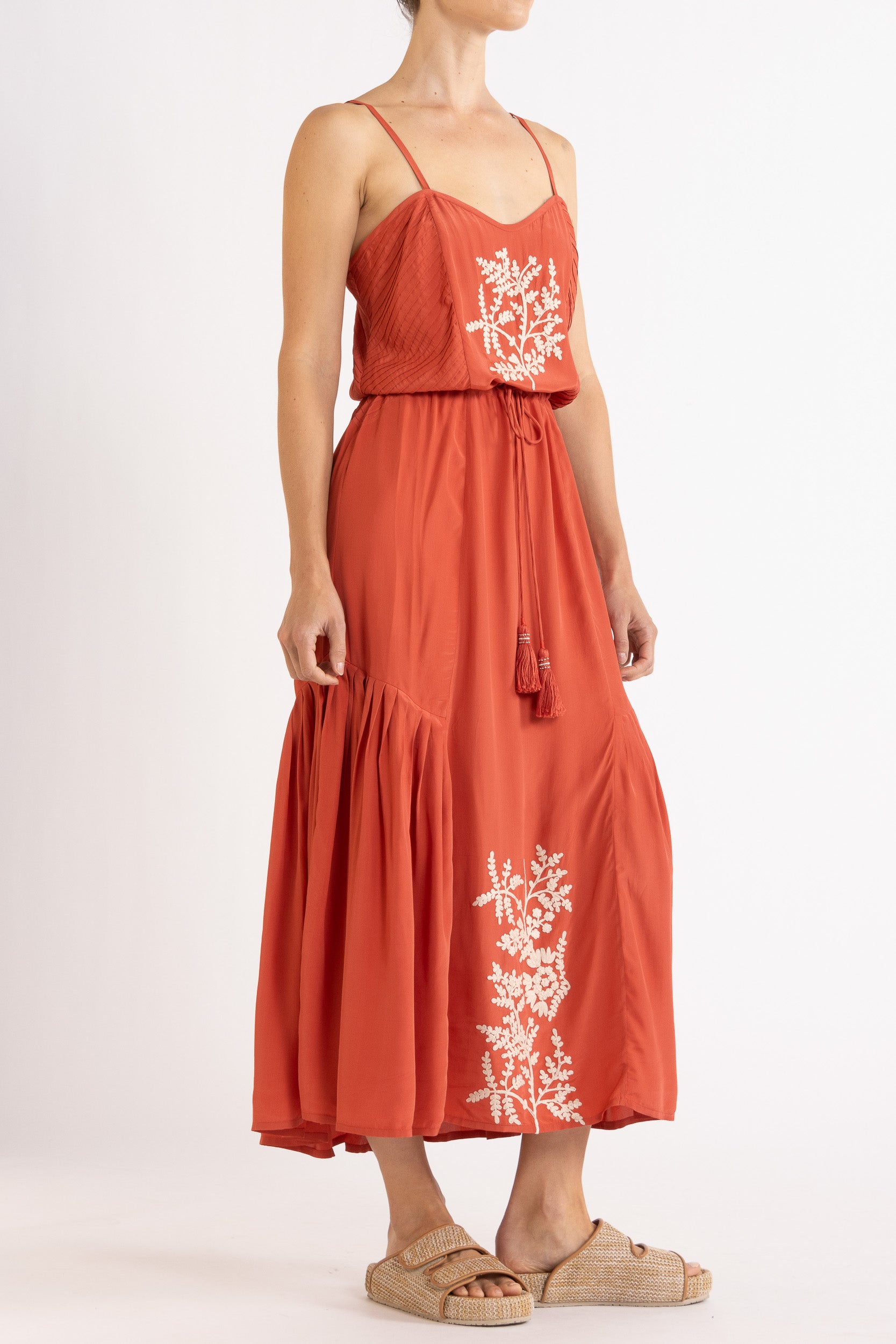 Woman wearing a red dress with floral embroidery on a white background