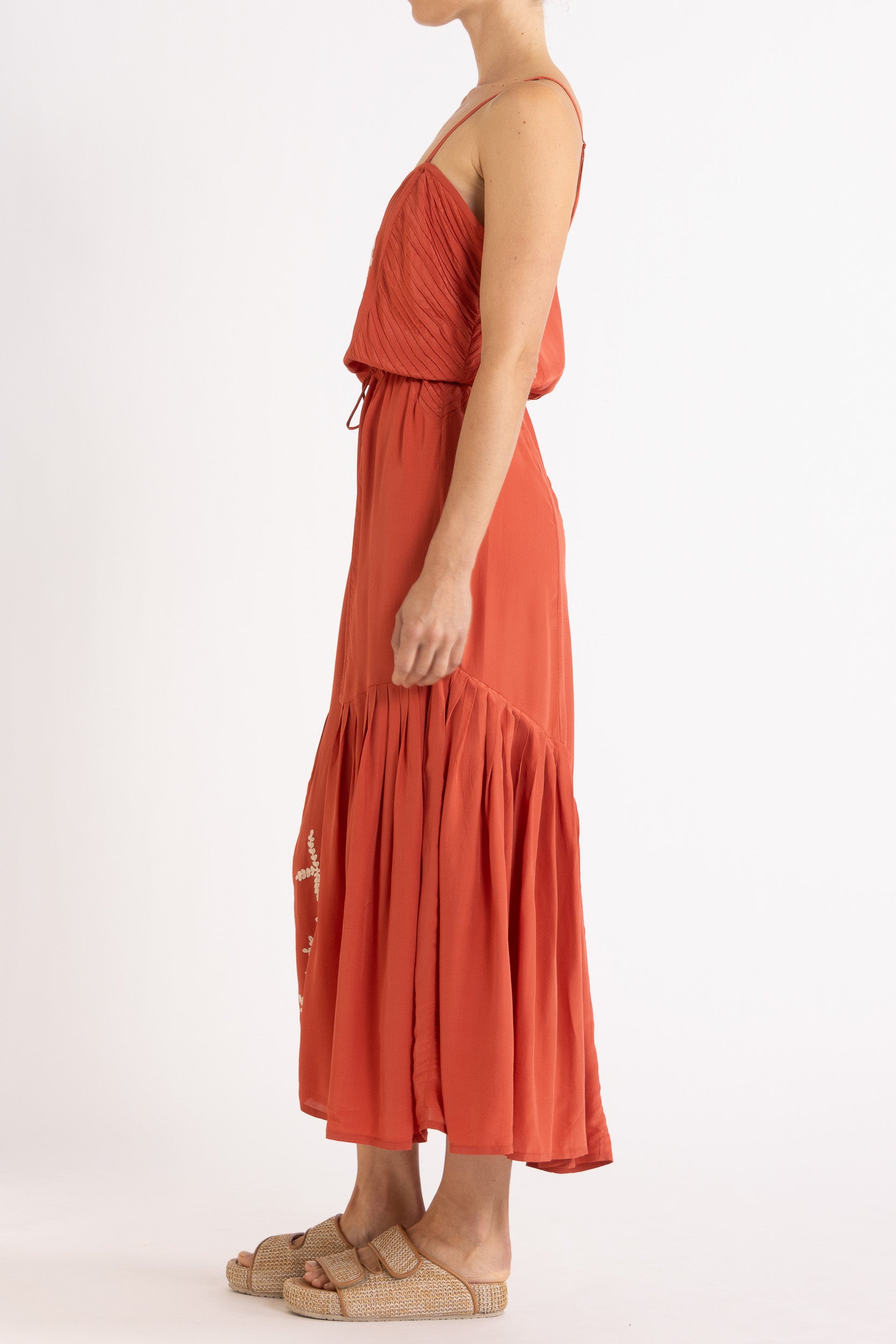 Woman wearing a red dress with floral embroidery on a white background