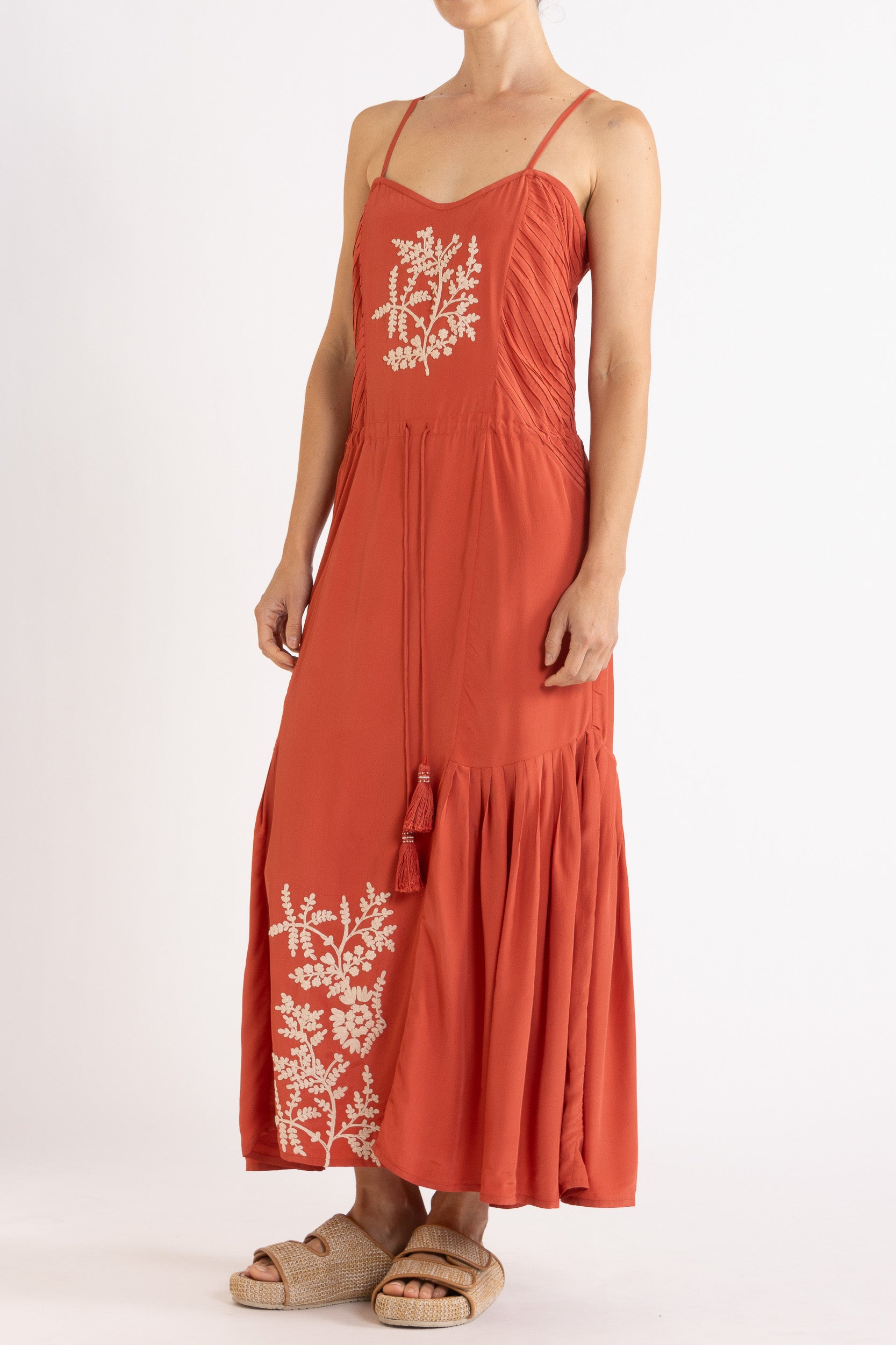 Woman wearing a red dress with floral embroidery on a white background