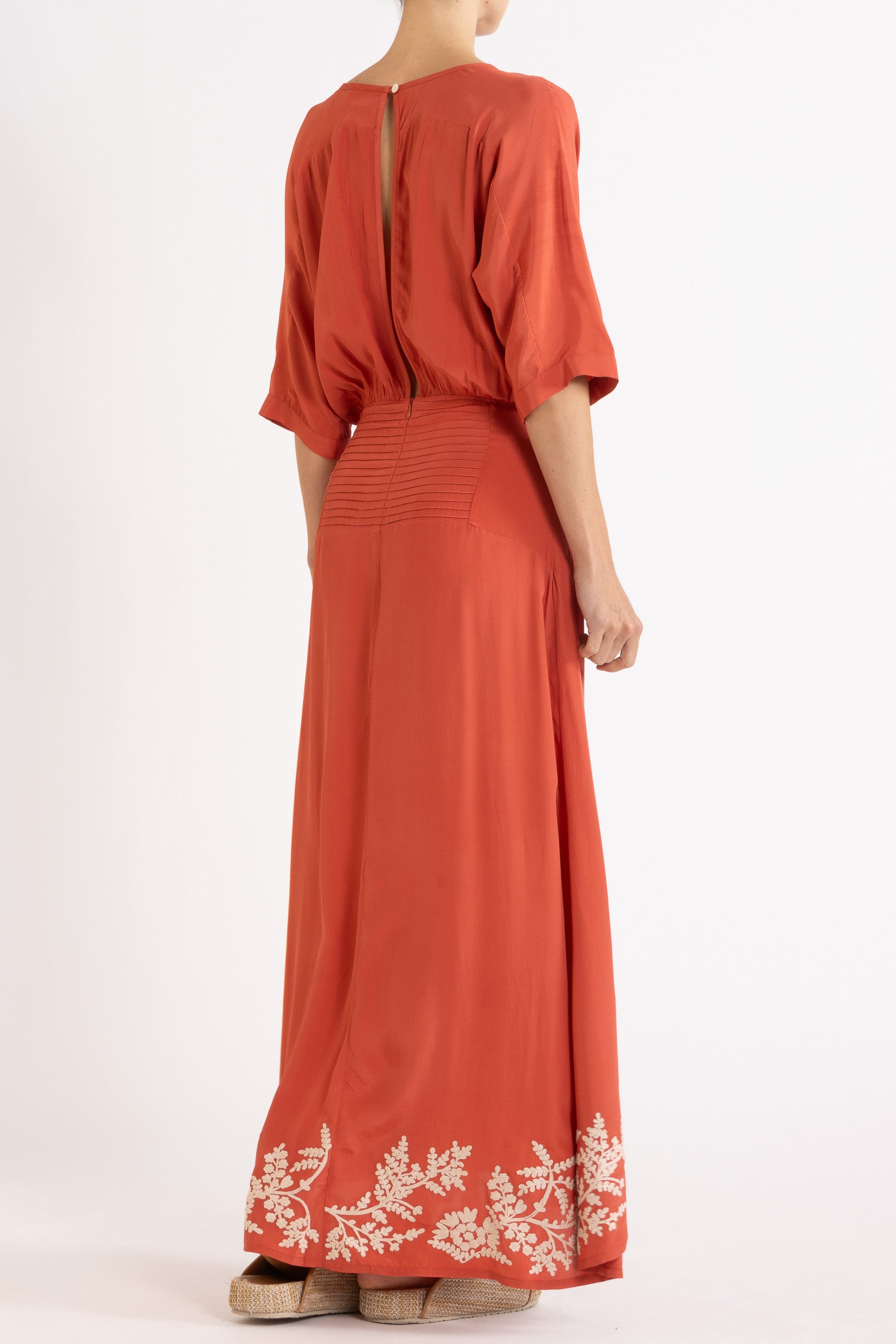 Woman wearing a red dress with floral embroidery on a white background