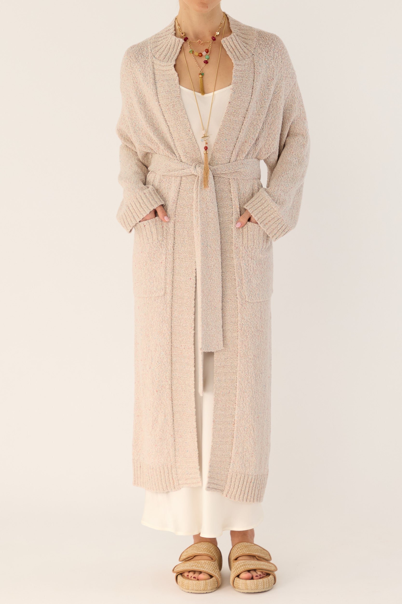 Model wearing beige knitted longline cardigan and white silk slip, front view