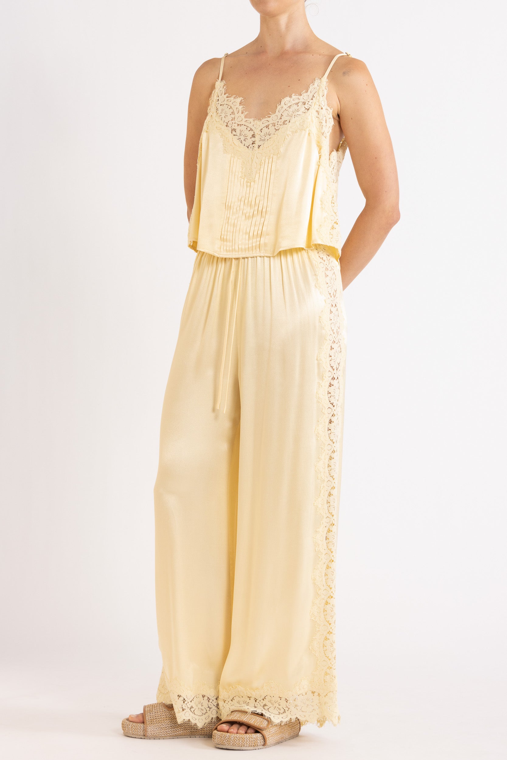 Woman wearing matching vanilla lace-trimmed camisole and pant.