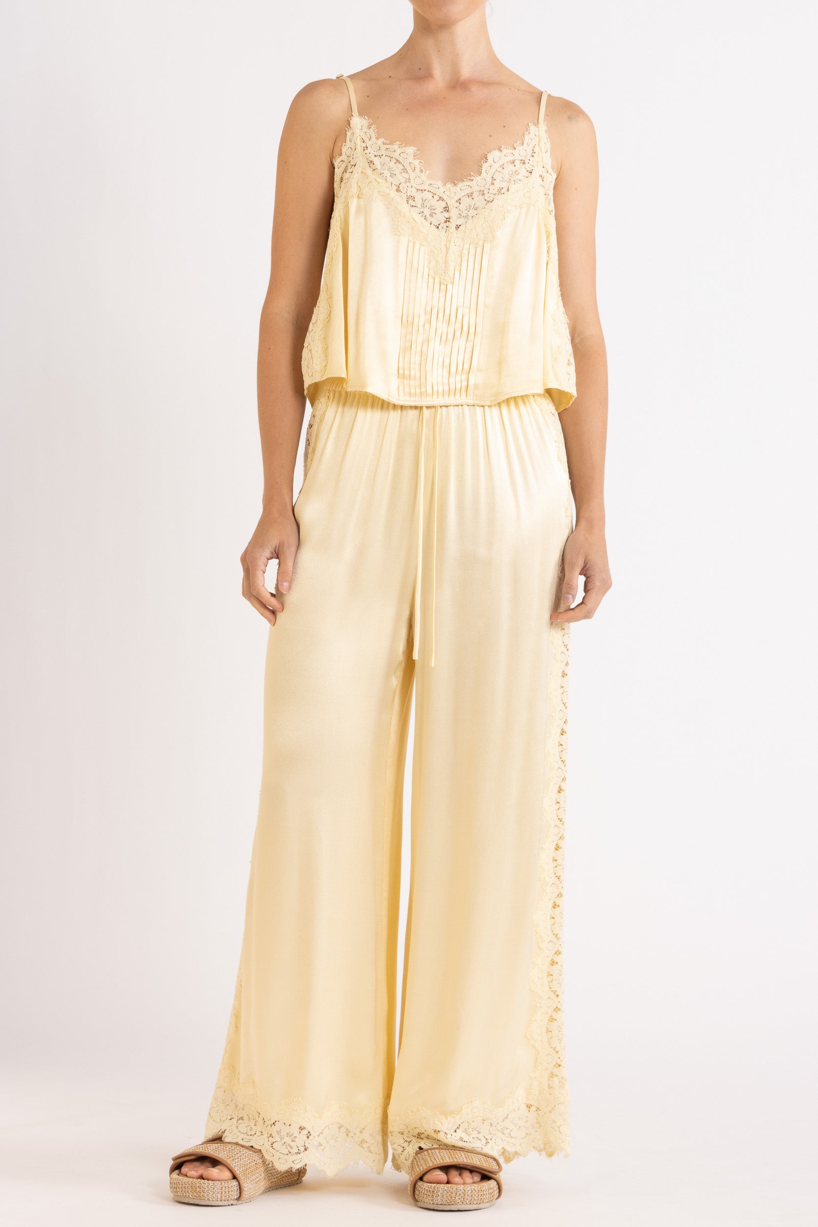 Woman wearing matching vanilla lace-trimmed camisole and pant.