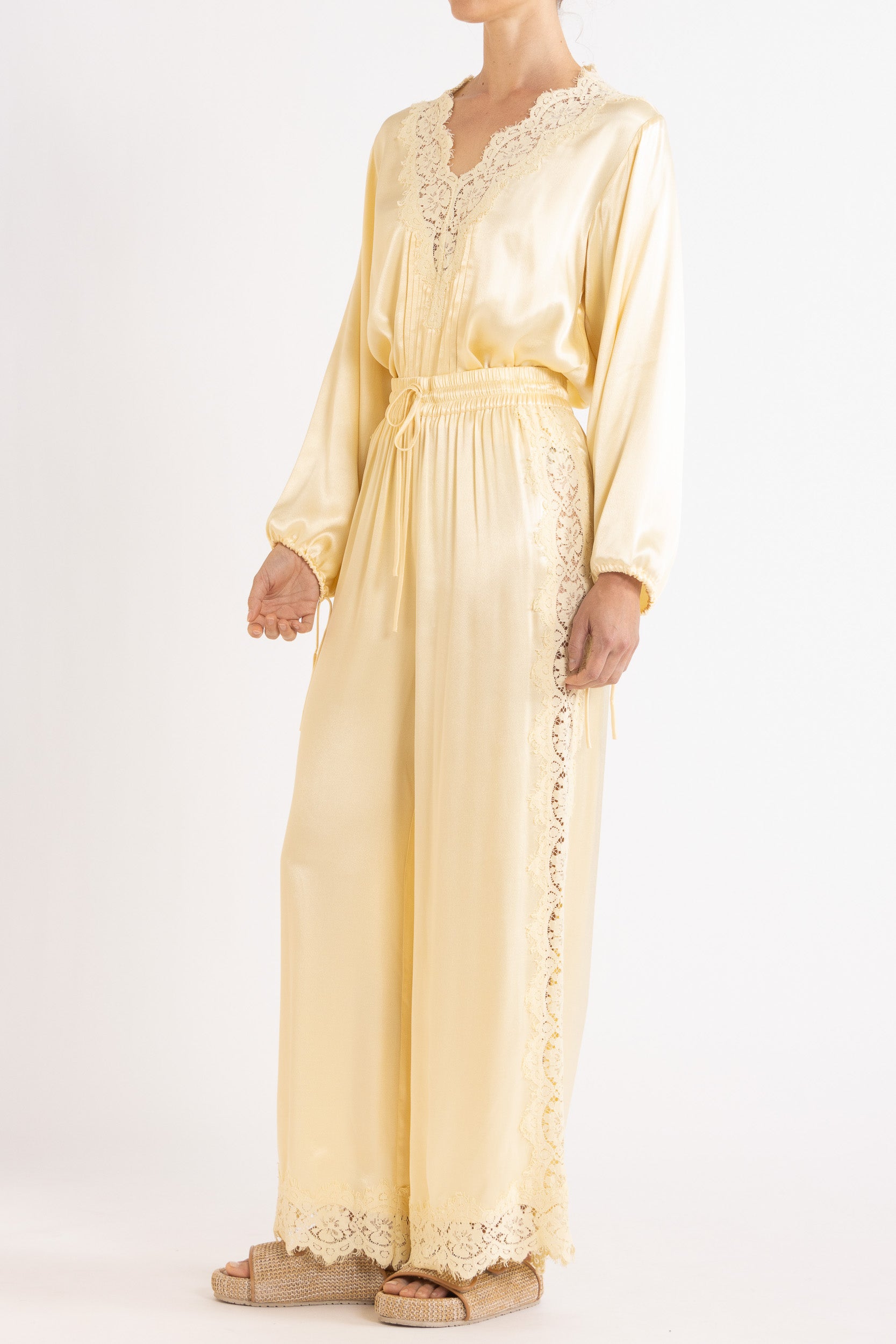 Woman wearing matching vanilla lace lined long sleeve top and pant with a white background.