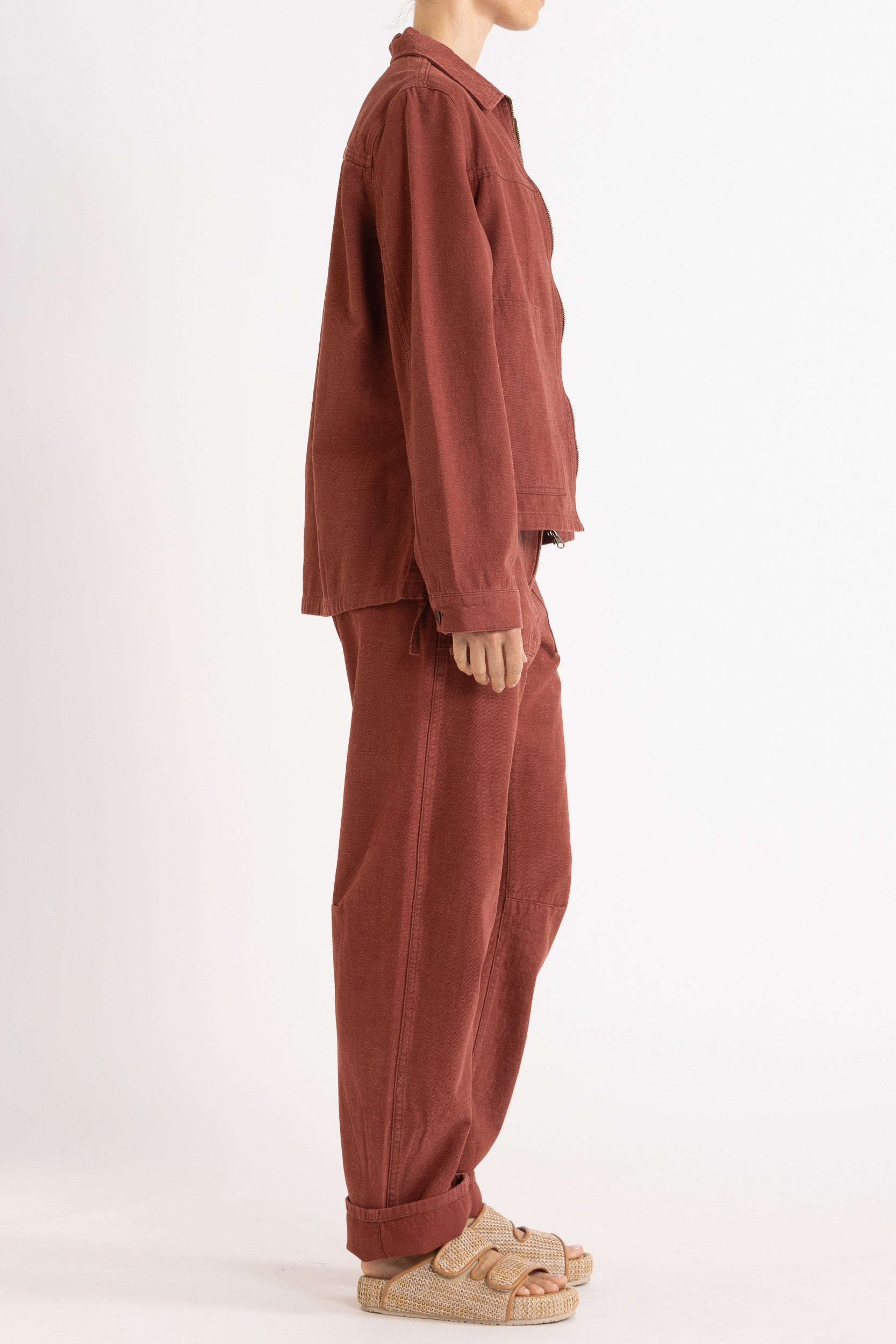 Model wearing burgundy cotton-twill utility jacket & pant, side view