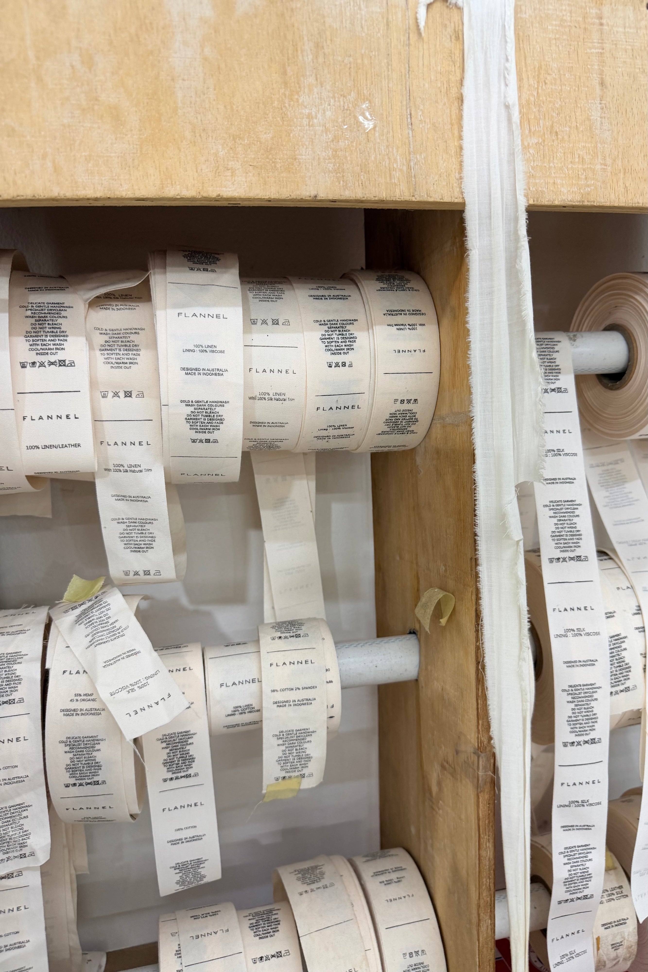 Image of FLANNEL clothing tags rolled, before being sewed. 