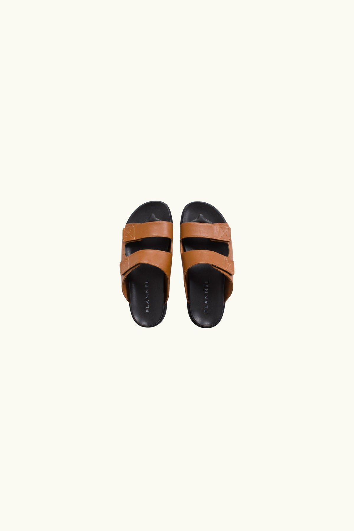 Pair of brown and black leather sandals on a white background