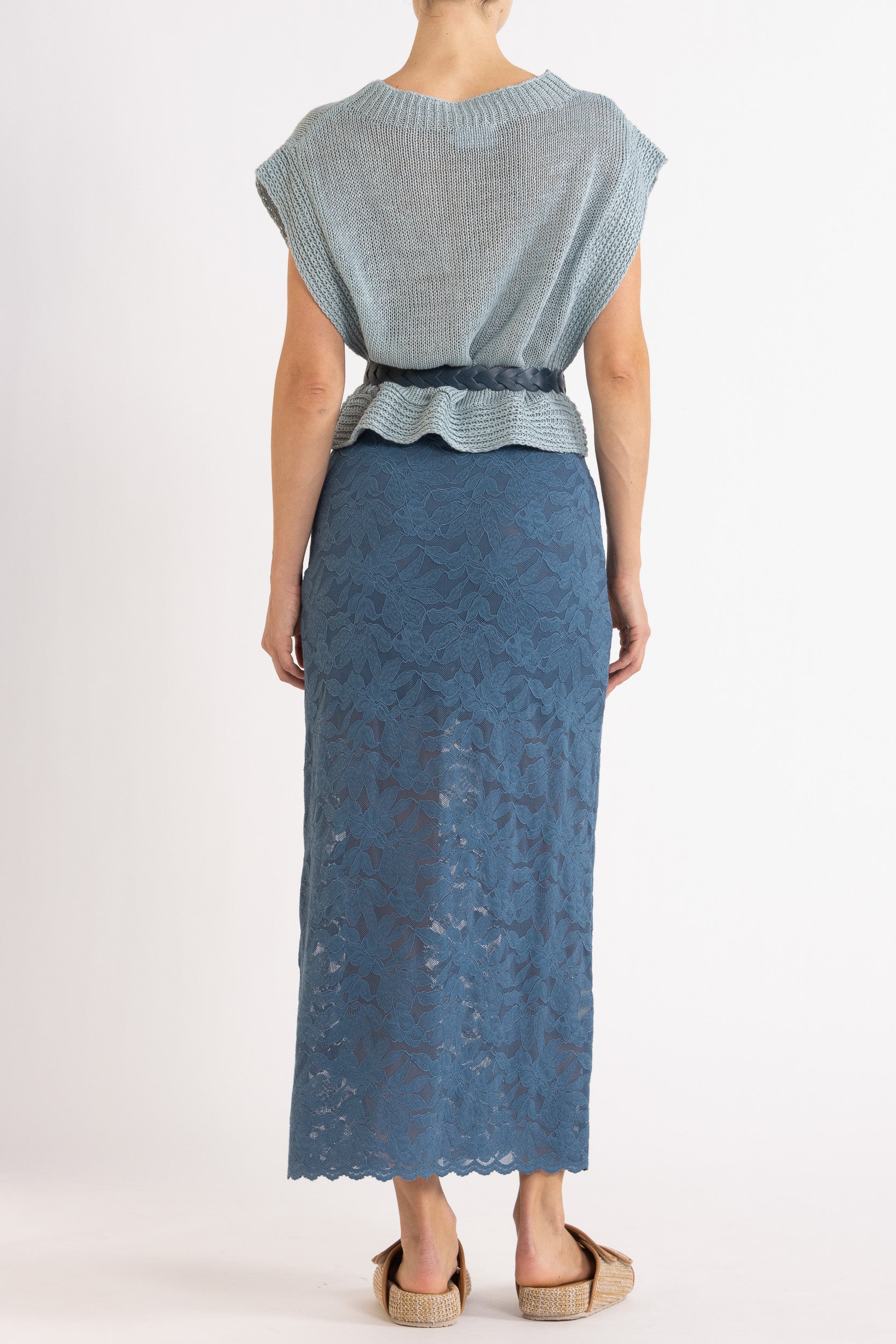 Woman wearing blue linen vest with a braided blue belt and a blue floral lace skirt.