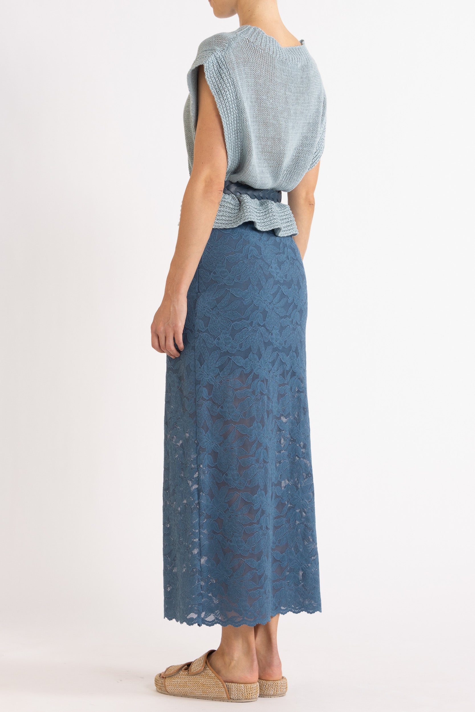 Woman wearing blue linen vest with a braided blue belt and a blue floral lace skirt.