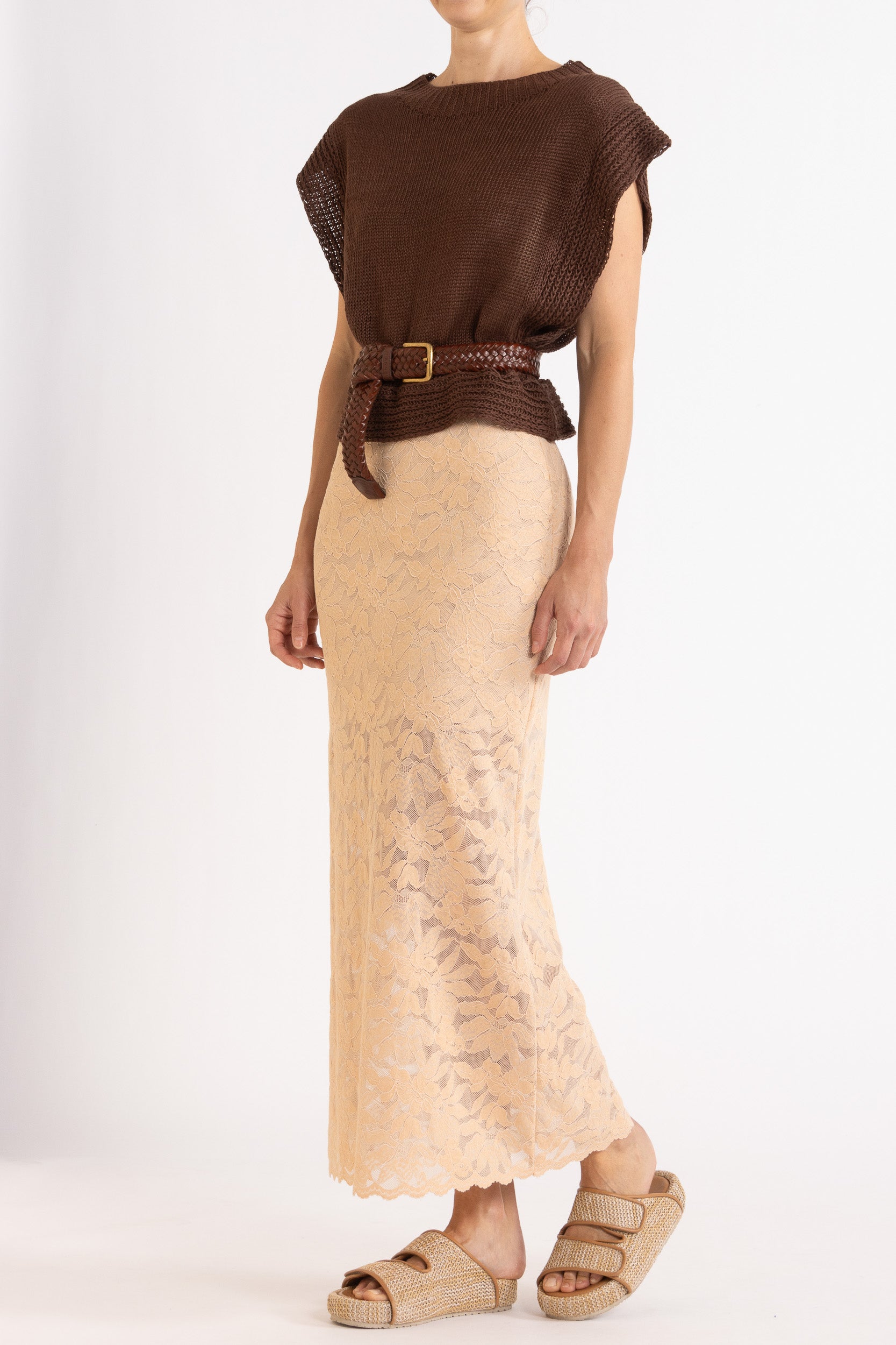 Woman wearing a brown linen vest, paired with a brown braided belt and a floral lace biscuit maxi skirt