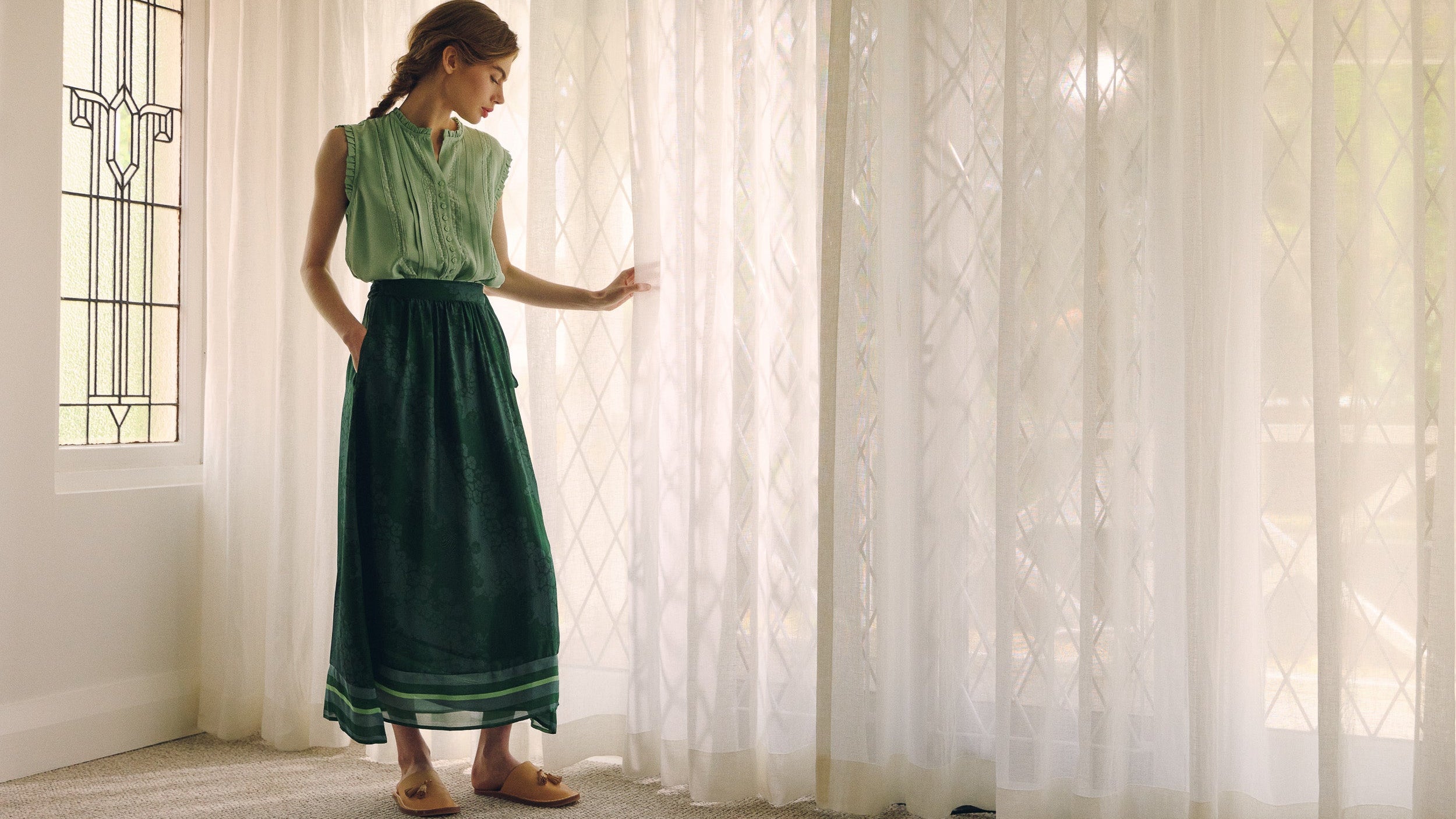 Person wearing a green top and dark green skirt against a neutral background
