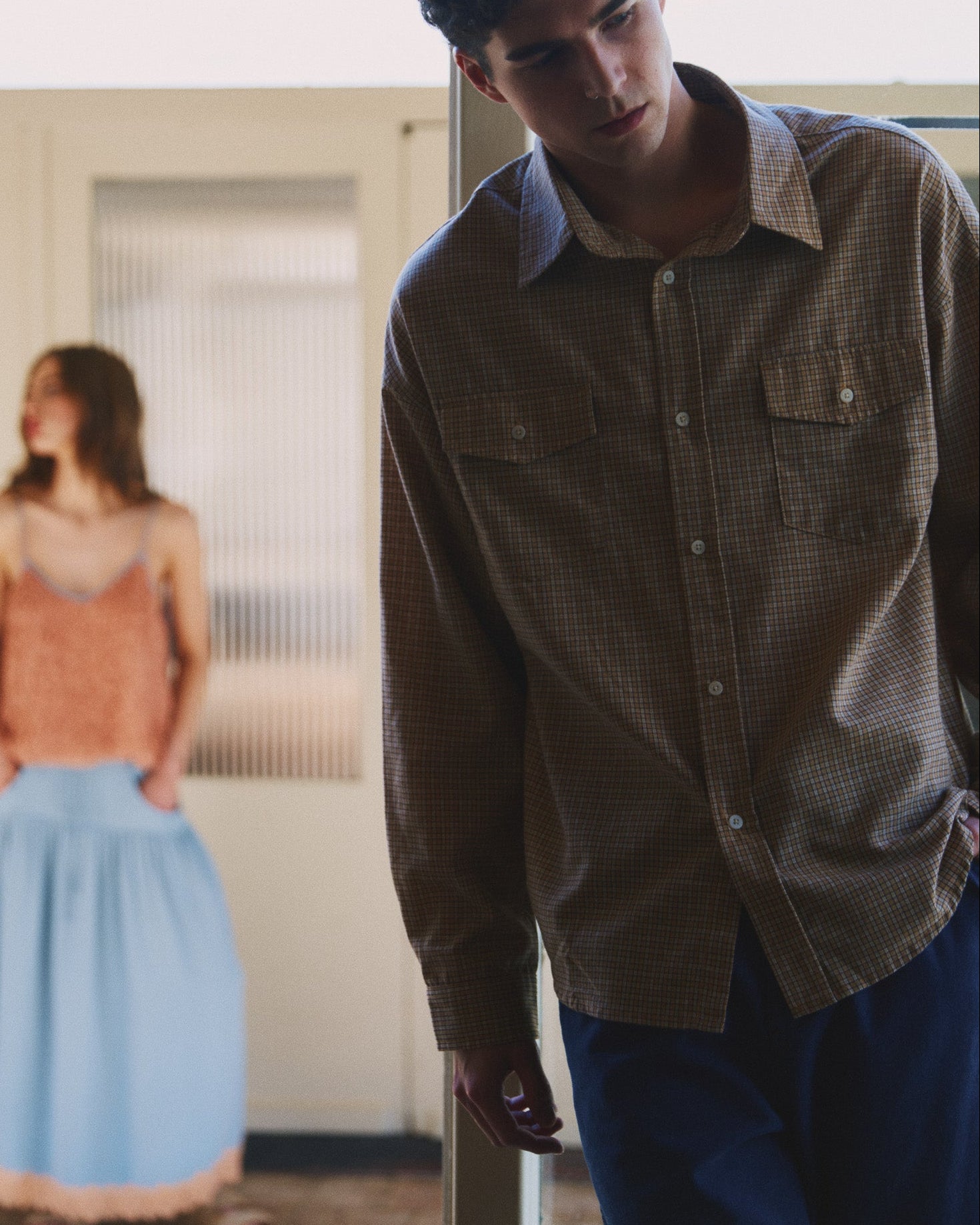 Man standing in a room with a woman in the background