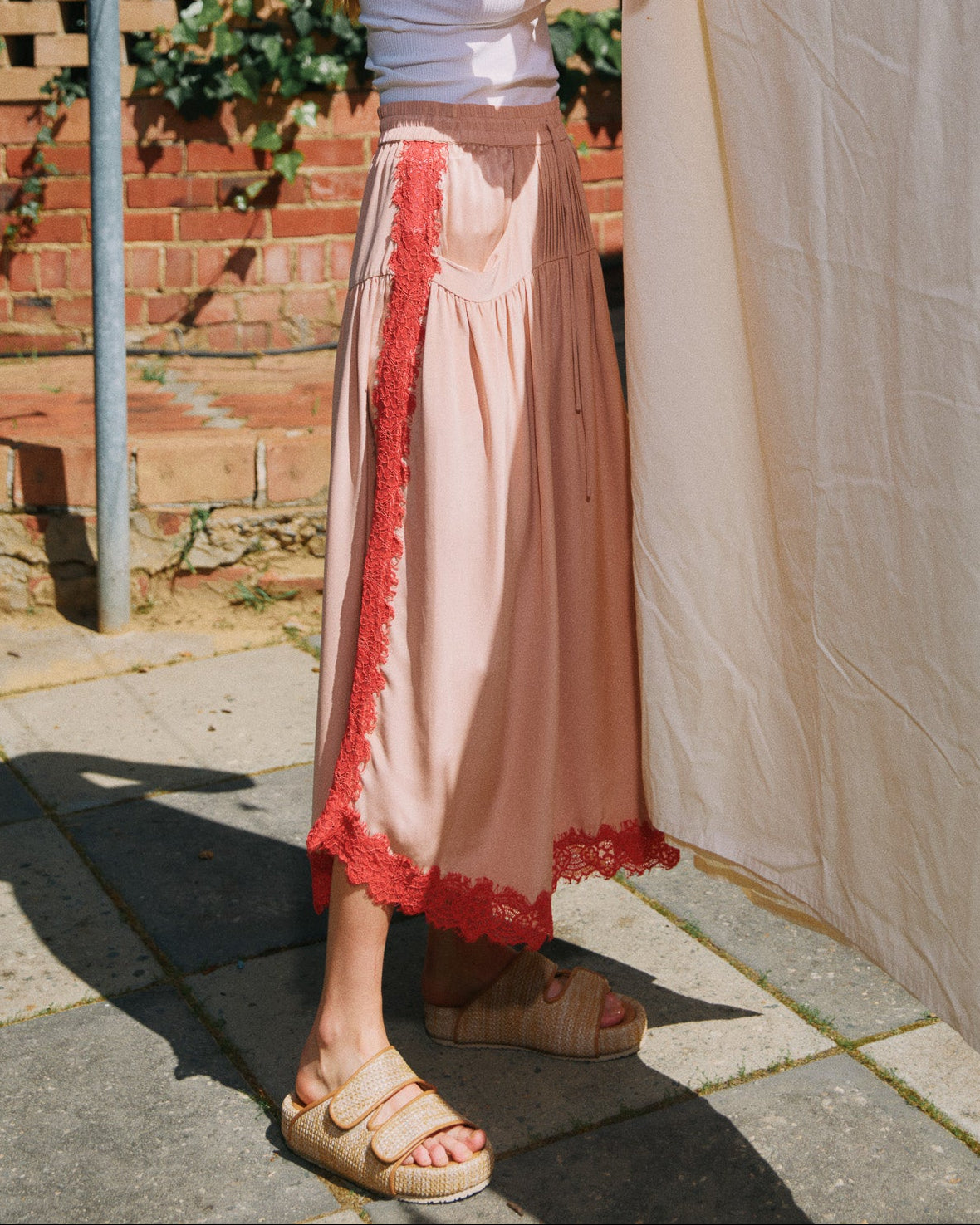 Woman hanging white fabric on a clothesline outdoors.