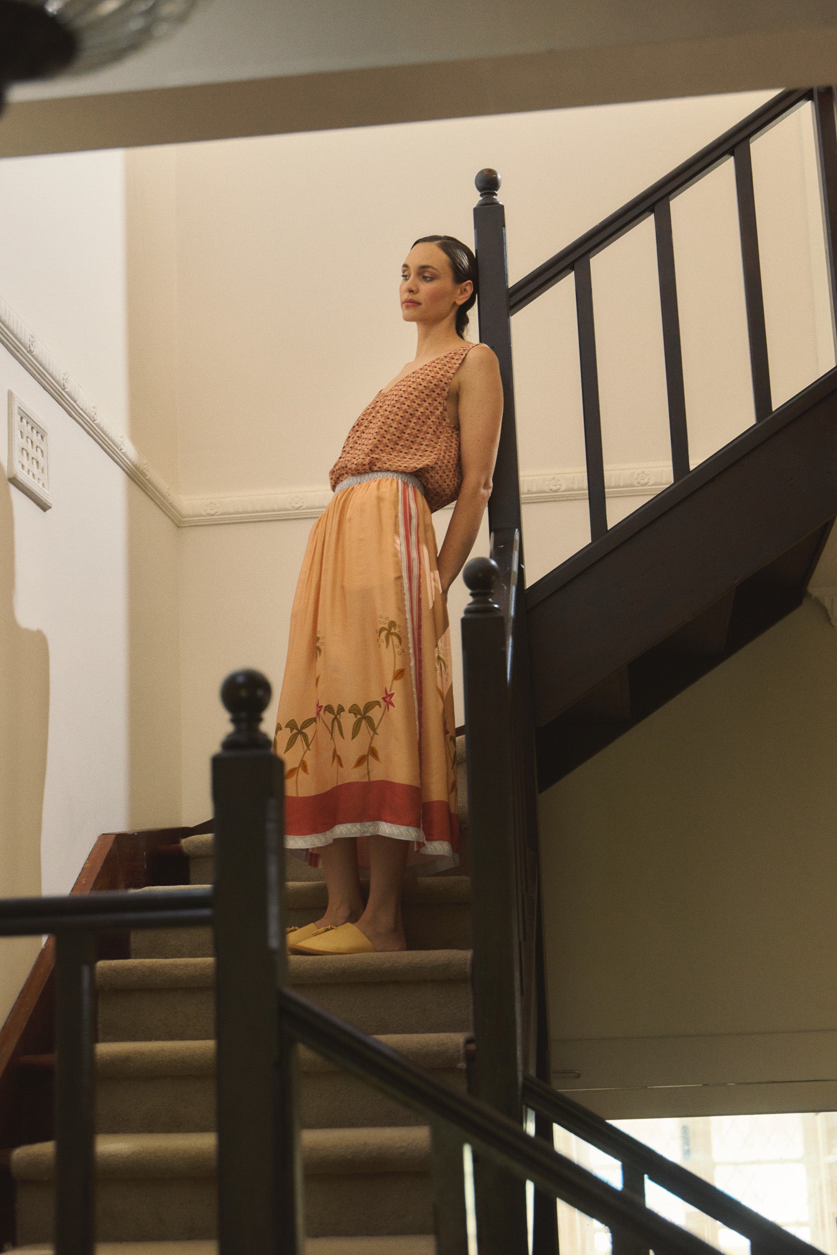 Model wearing peach patterned tank and printed skirt, campaign image