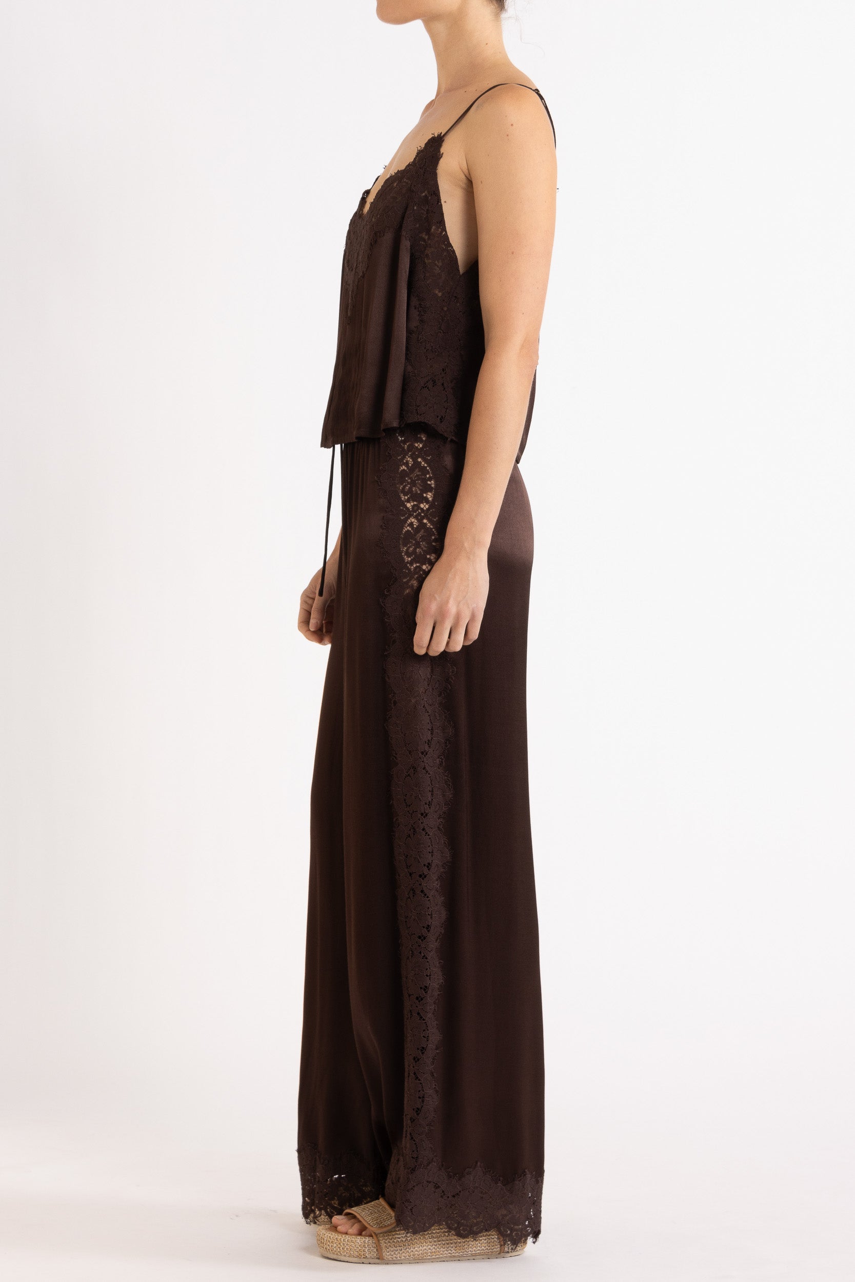 Woman wearing matching brown camisole and pant on a white background