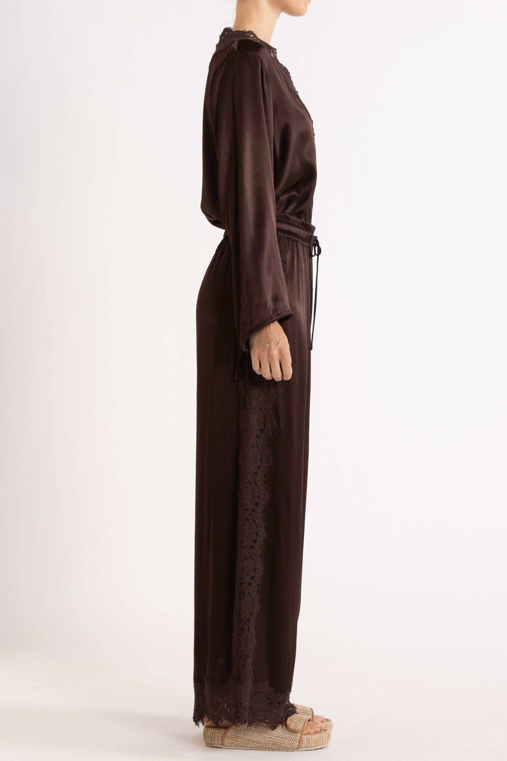 Woman wearing a brown long sleeve top and pant with lace details on a white background