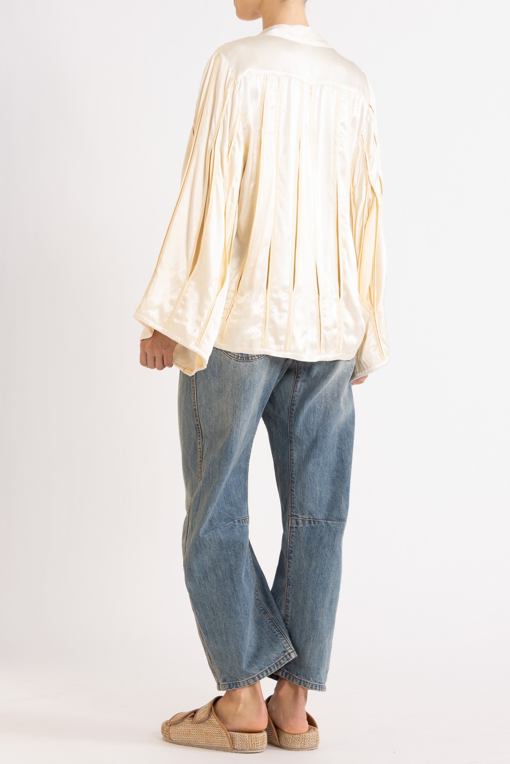 Model wearing cream box pleat jacket, white lace camisole & denim jean, side-back view