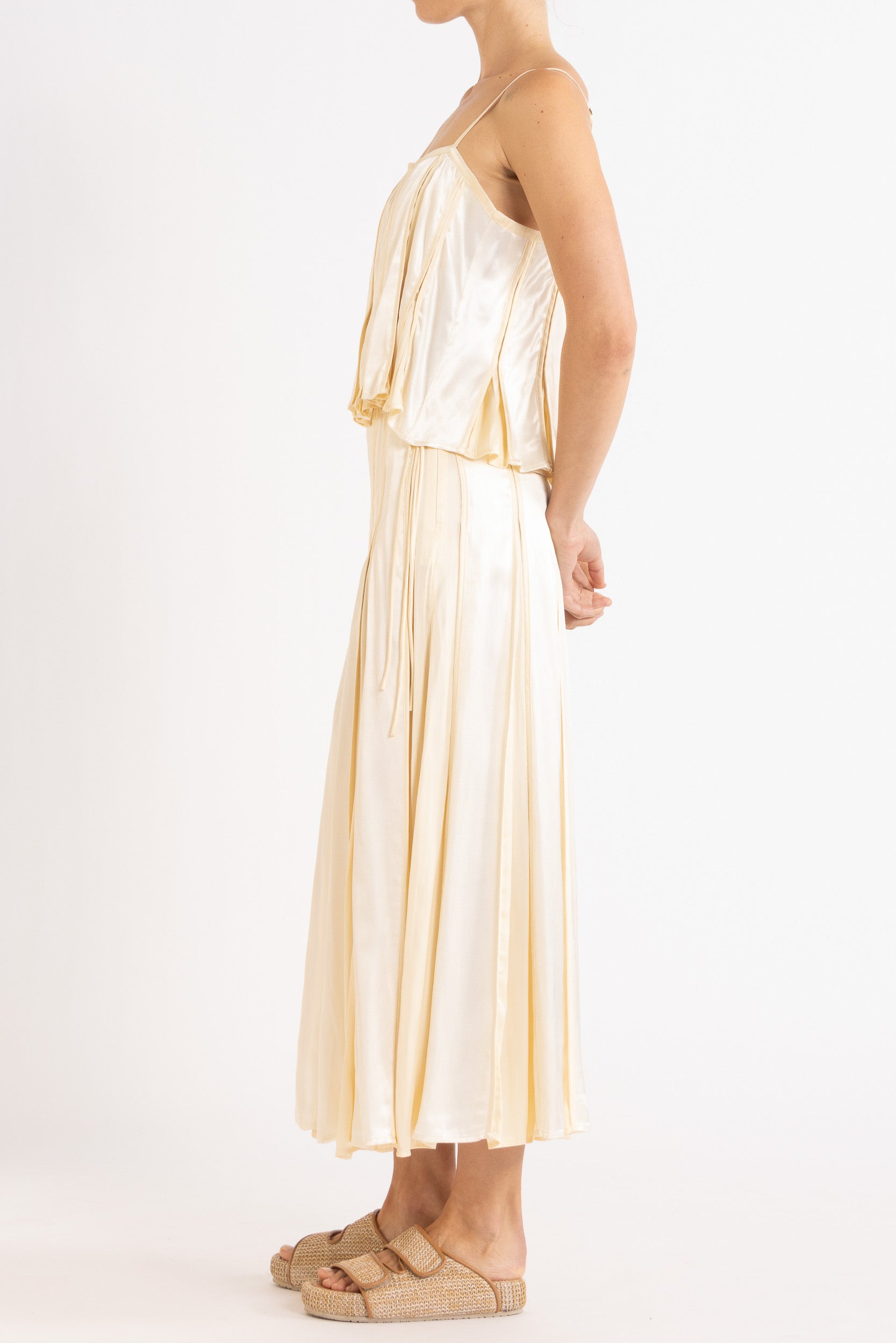 Model wearing cream box pleat camisole & skirt, side view