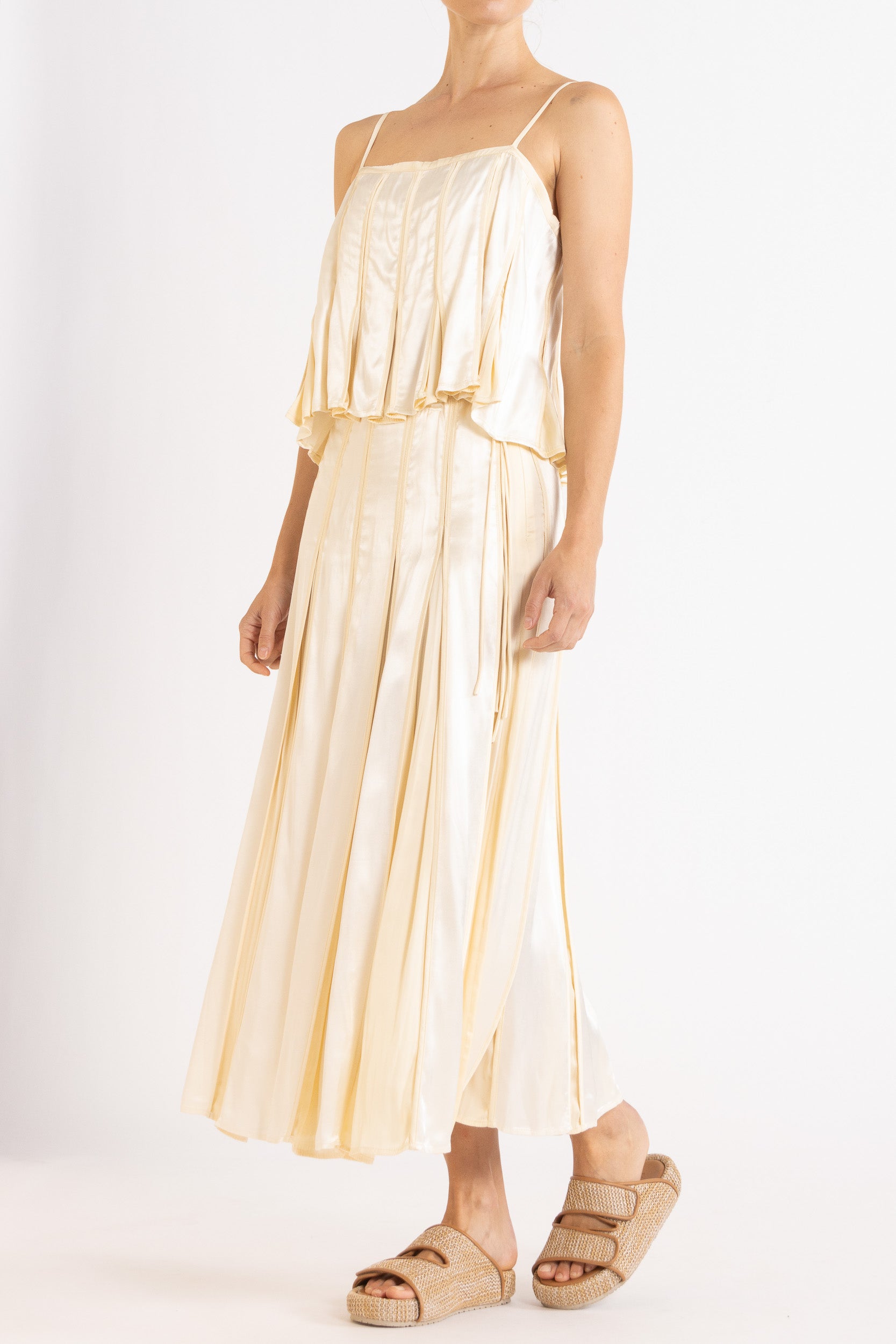 Model wearing cream box pleat camisole & skirt, front-side view