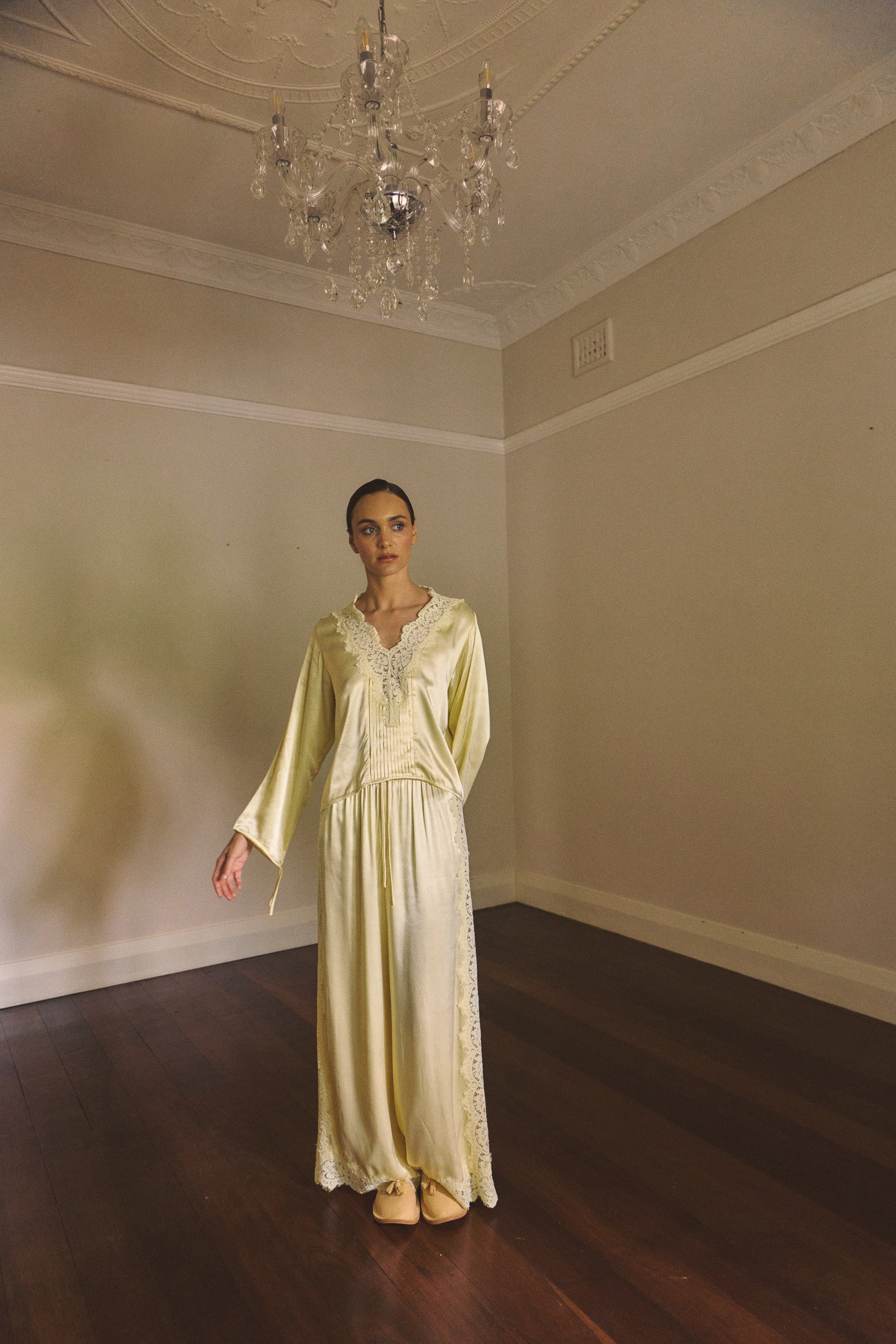 Woman in an empty room wearing matching vanilla lace lined long sleeve top and pant. 