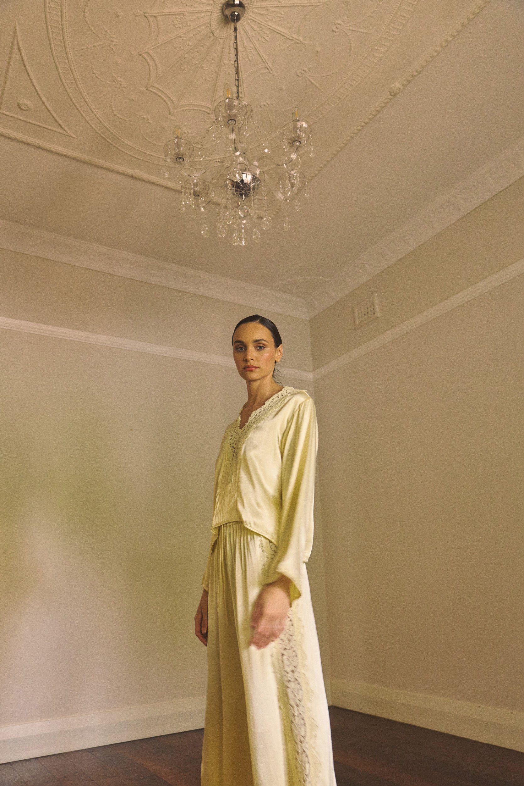 Woman standing in an empty room wearing a matching vanilla lace-lined long sleeve top with pant