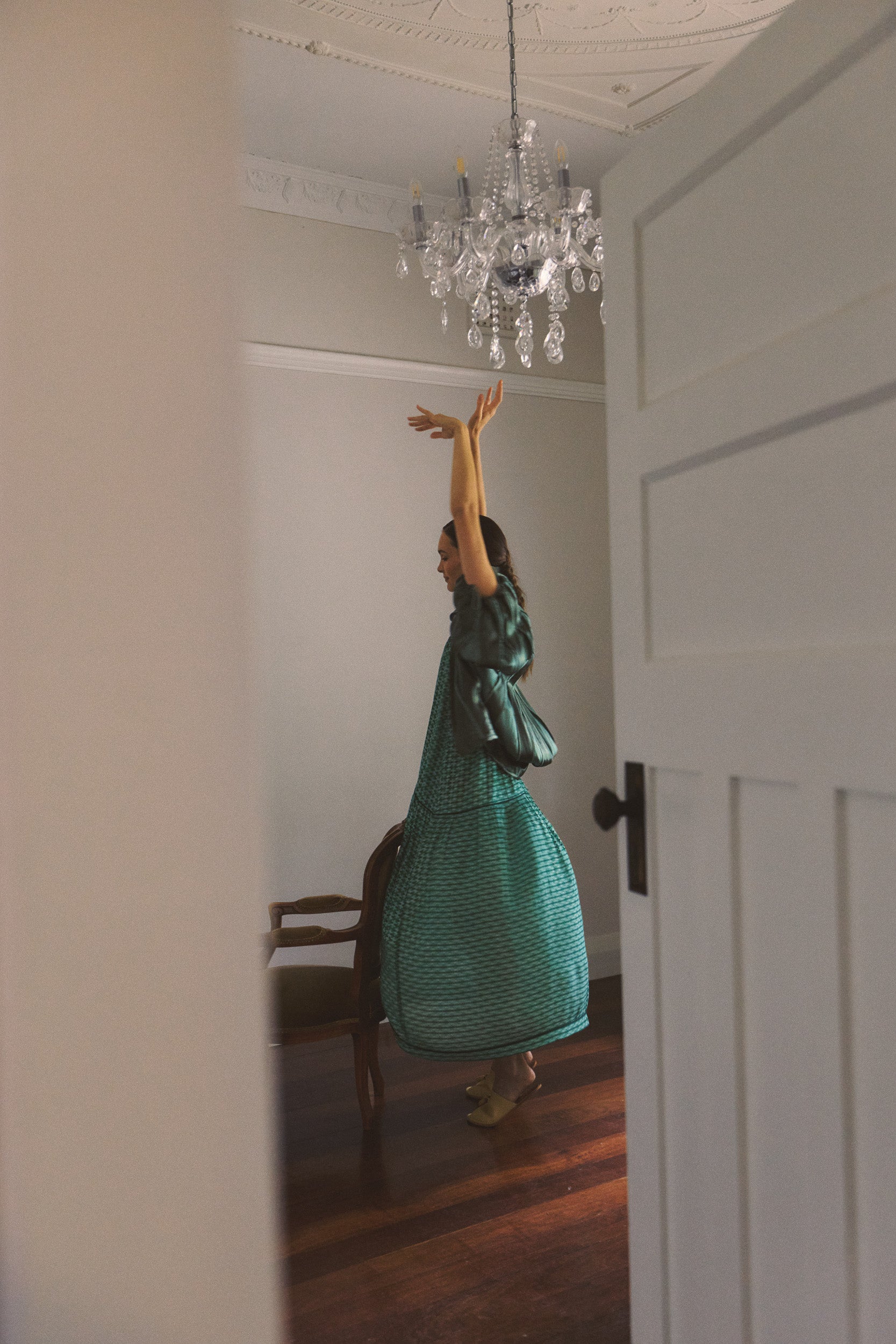 Model wearing green patterned dress and green jacket, campaign image