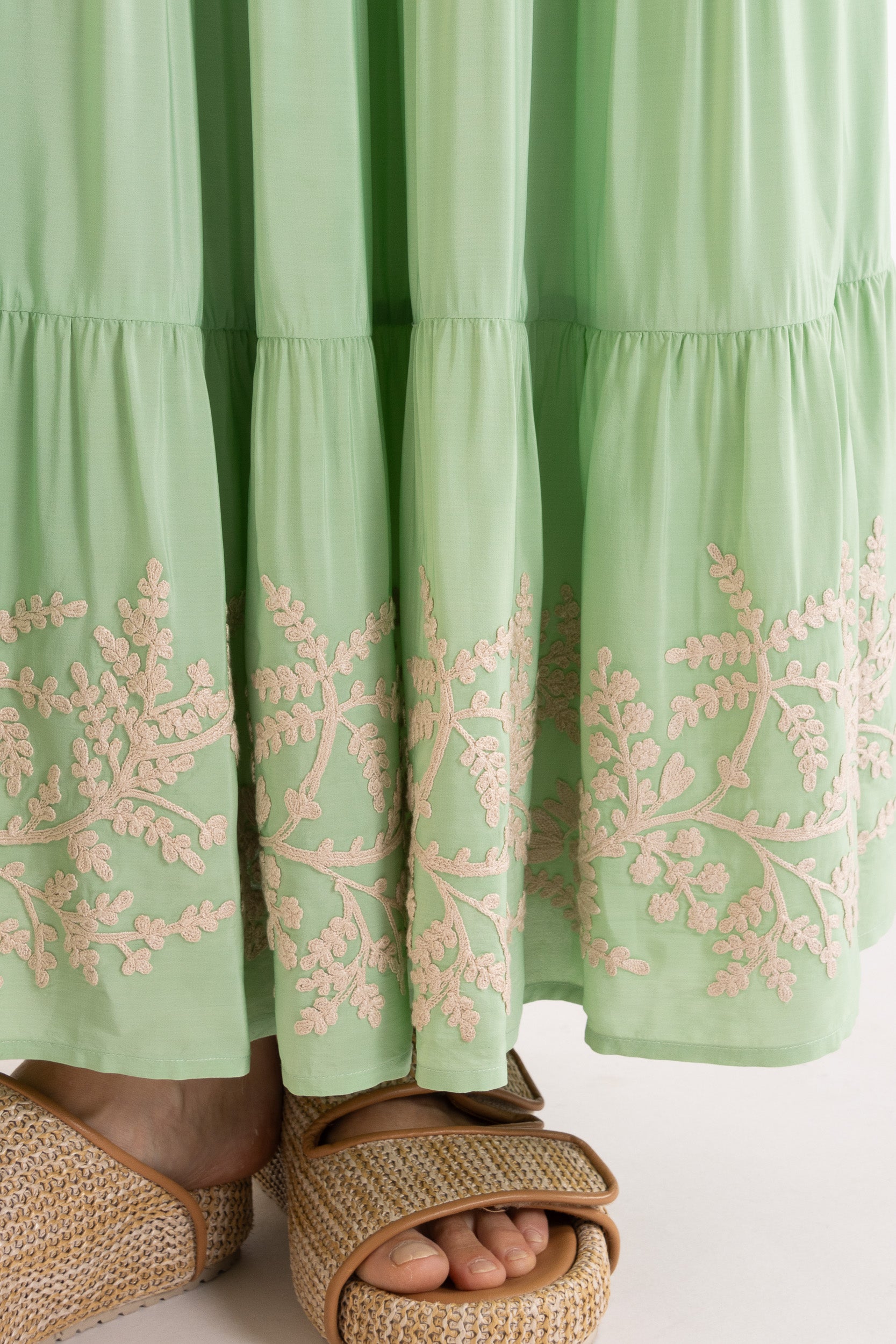 Light green skirt with floral embroidery worn by a person, on a white background