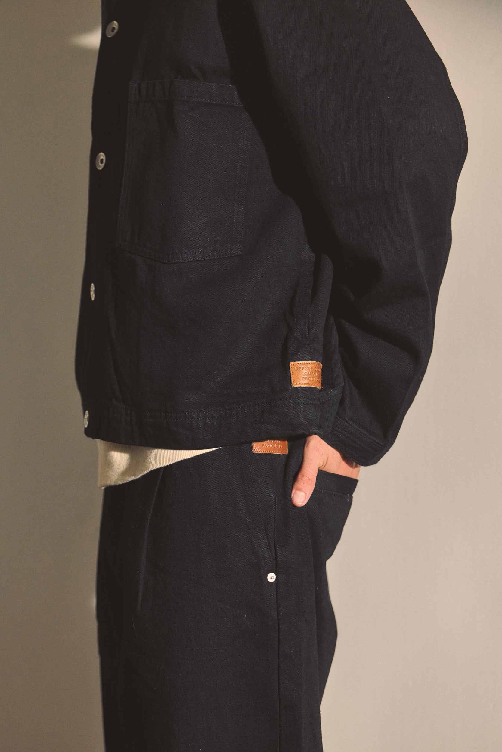 Close up image of male model wearing a Black matching jacket and pant set. 