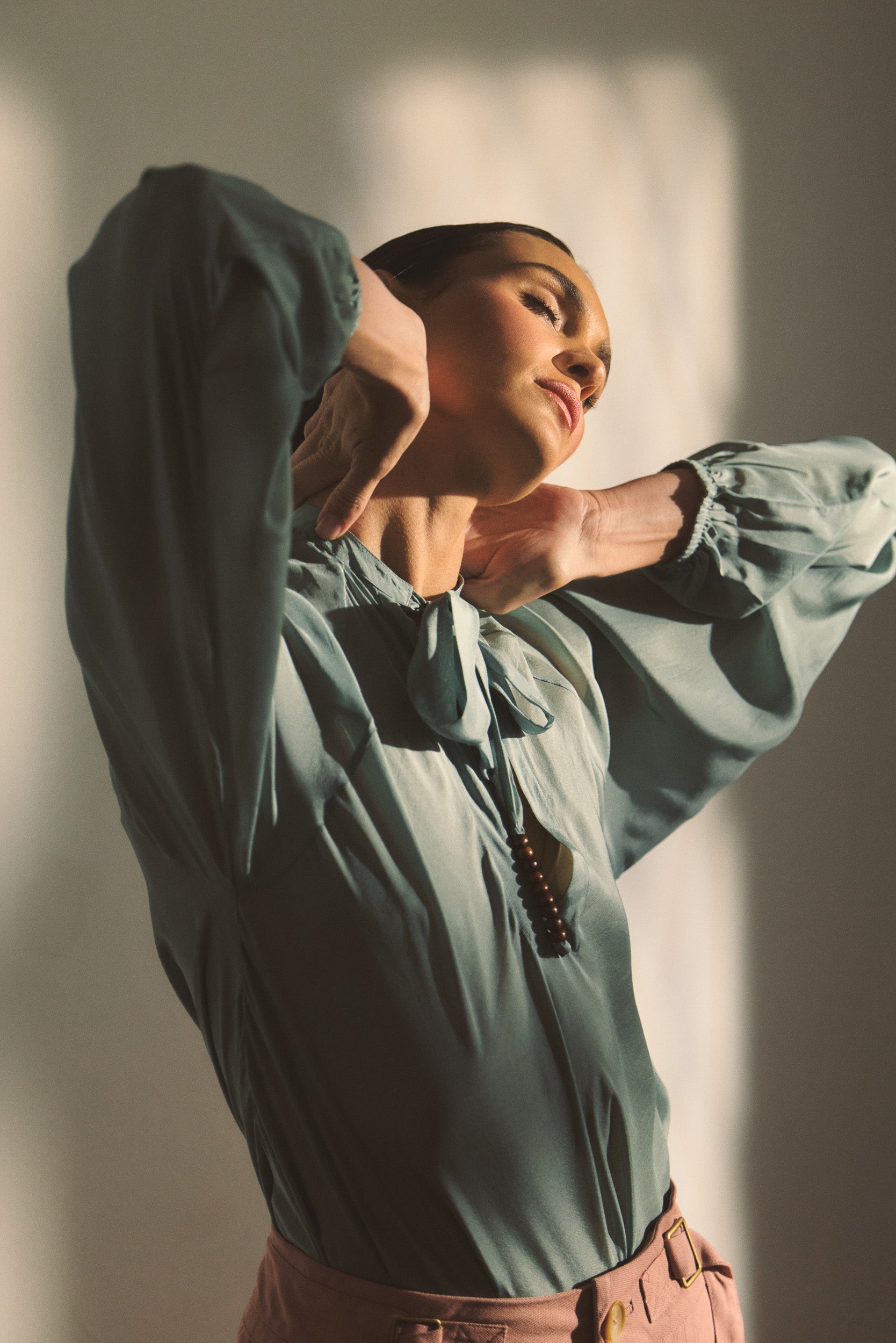 Model wearing blue silk shirt and pink pants. 