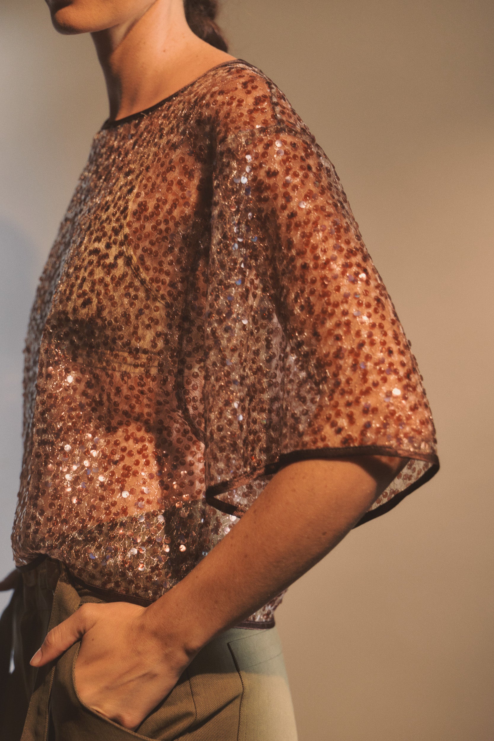 Model wearing mocha coloured sequin short sleeve shirt. 