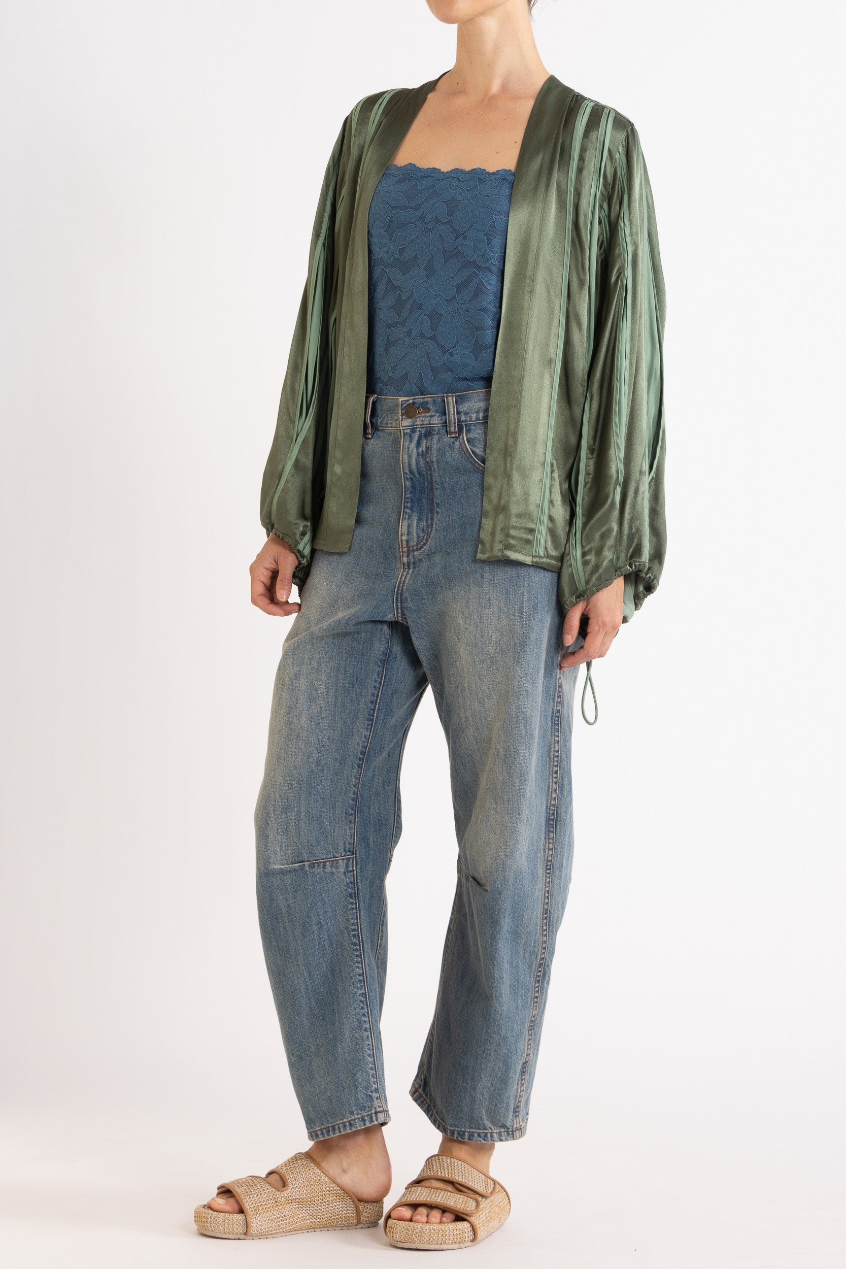 Model wearing green box pleat jacket, blue lace camisole & denim jean, front-side view