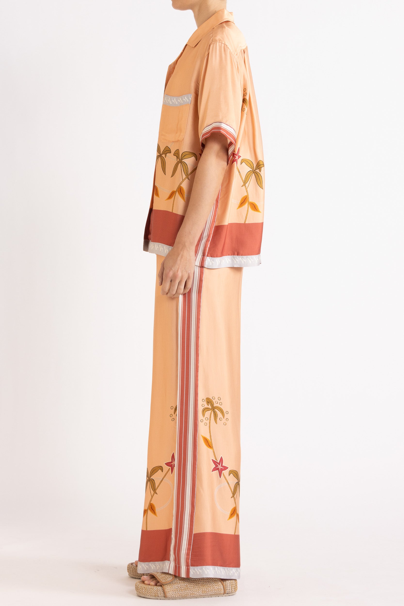 Woman wearing a matching peach short sleeve shirt and pants featuring floral patterns on a white background