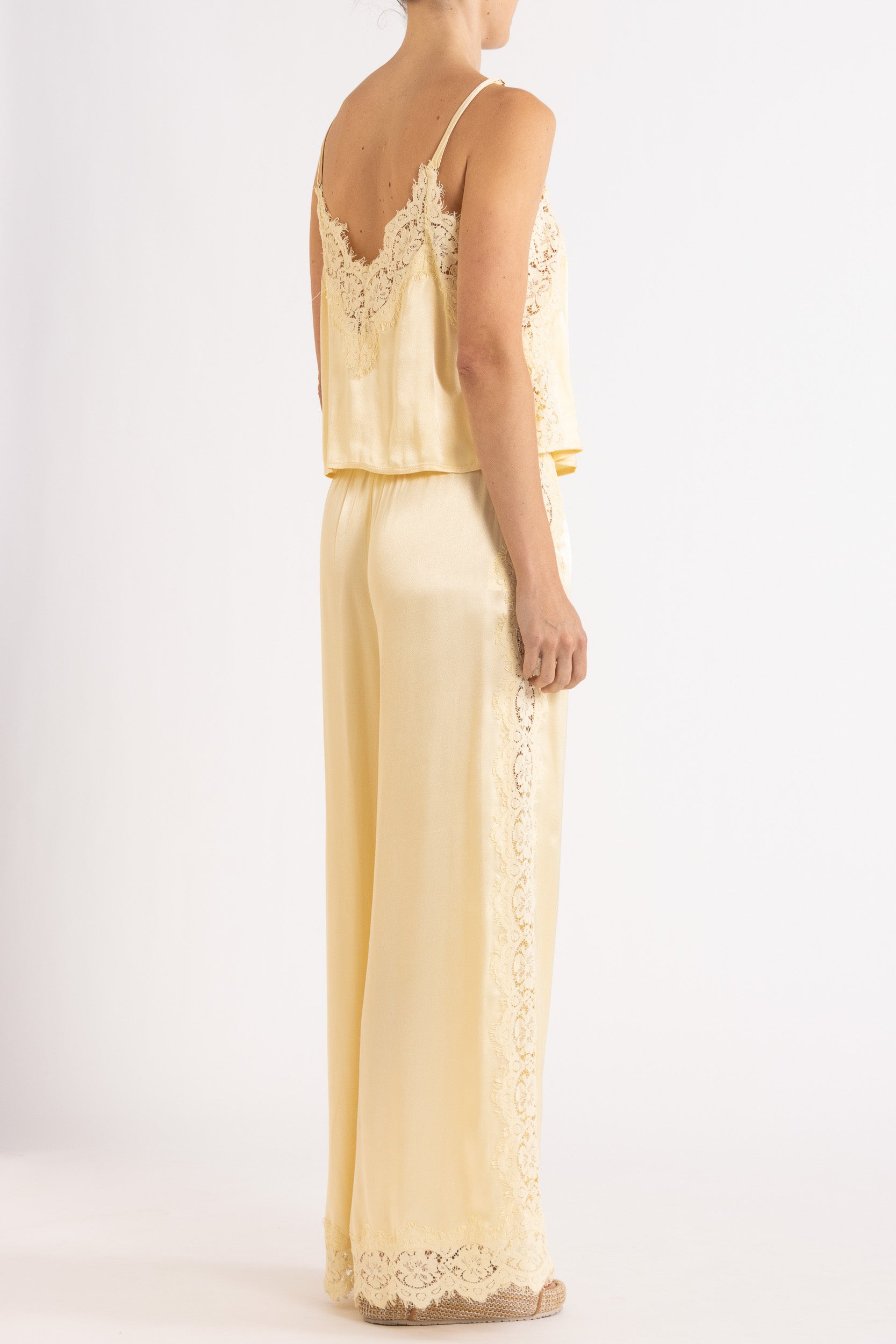 Woman wearing matching vanilla lace-trimmed camisole and pant.