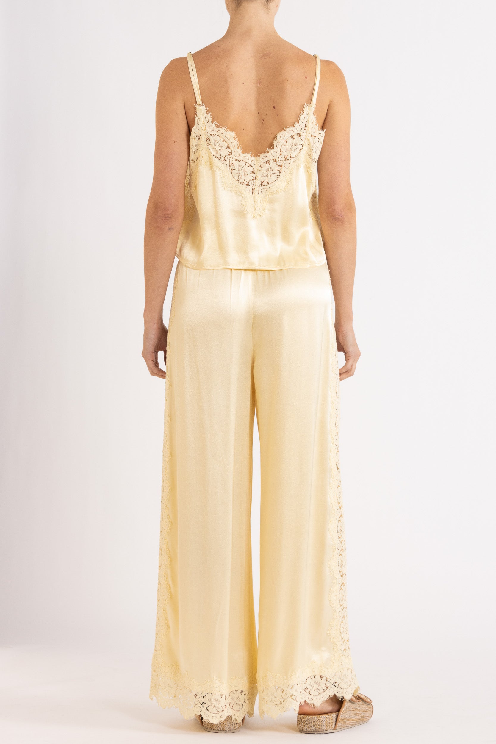 Woman wearing matching vanilla lace-trimmed camisole and pant.