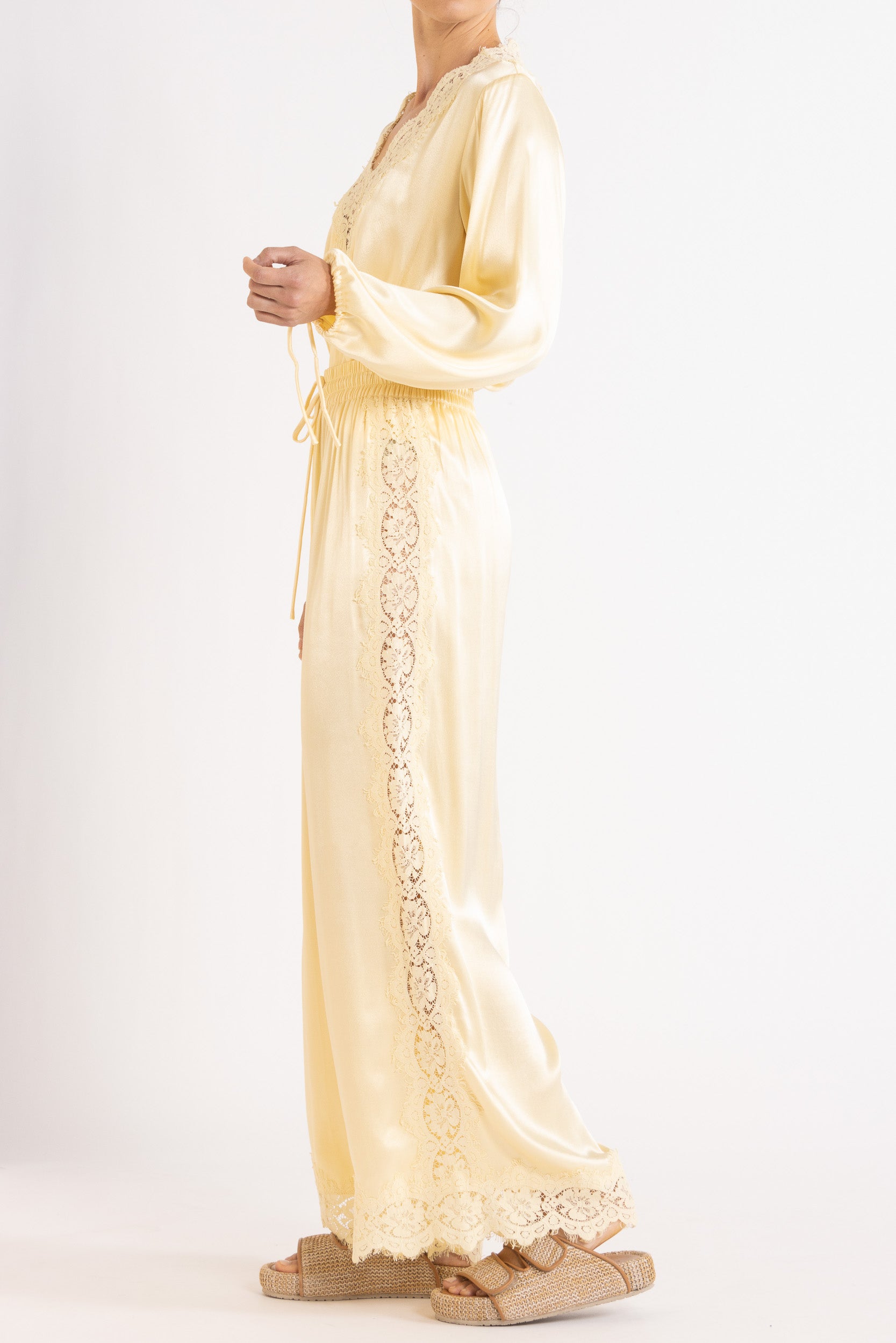 Woman wearing matching vanilla lace lined long sleeve top and pant with a white background.